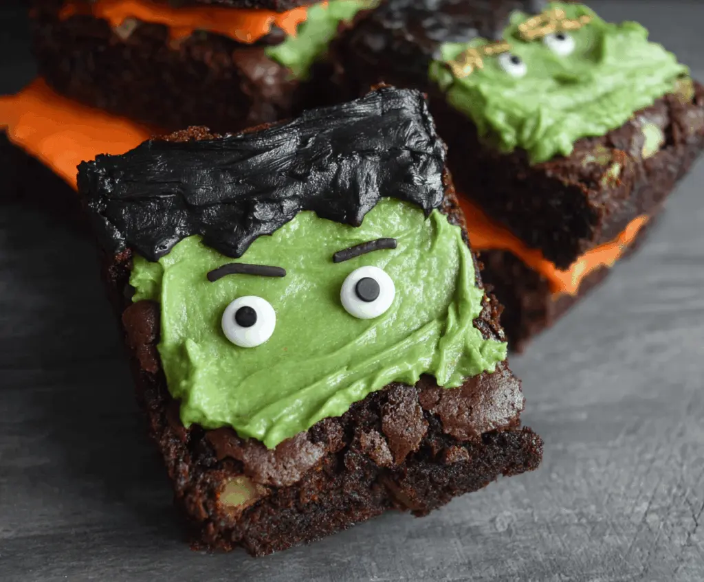 Delicious Frankenstein Brownies with green frosting, chocolate eyeballs, and spooky decorations perfect for Halloween dessert