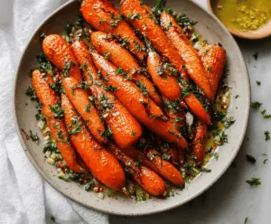Golden honey glazed roasted carrots garnished with fresh herbs, served as a healthy side dish.