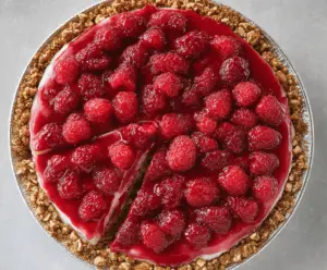 Delicious no-bake raspberry pretzel pie garnished with fresh raspberries and whipped cream.