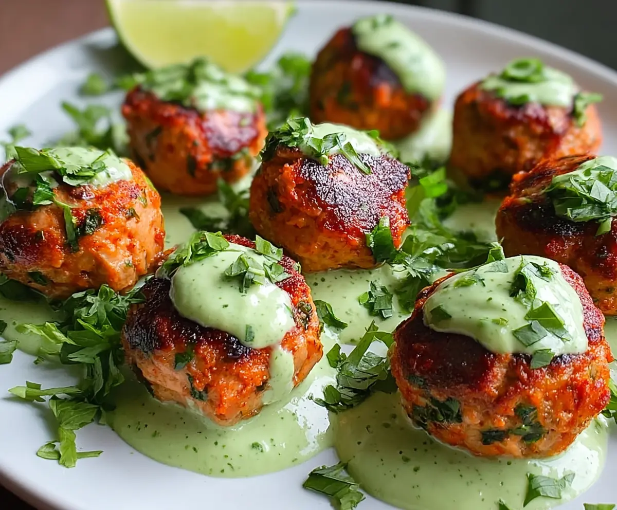 Delicious baked salmon meatballs topped with a creamy tangy avocado sauce, perfect for a healthy meal.