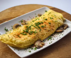 Delicious classic omelet filled with fluffy eggs and melted cheese, served on a white plate.