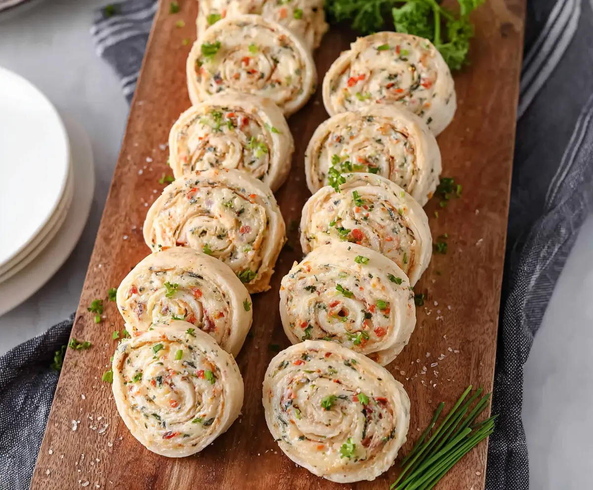 Delicious cream cheese pinwheels with flaky pastry and savory filling on a wooden serving platter.