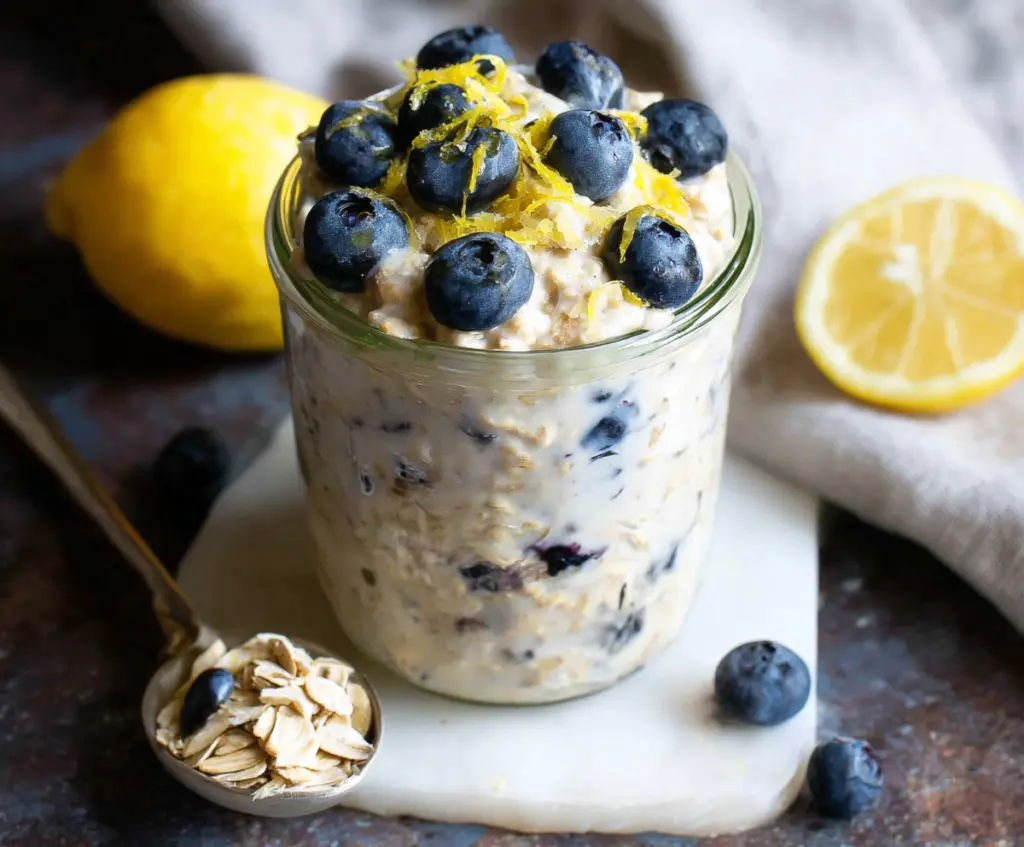 Creamy blueberry lemon overnight oats in a glass jar topped with fresh blueberries and lemon zest.