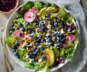 Colorful blueberry pistachio spring salad with fresh greens and vibrant toppings.