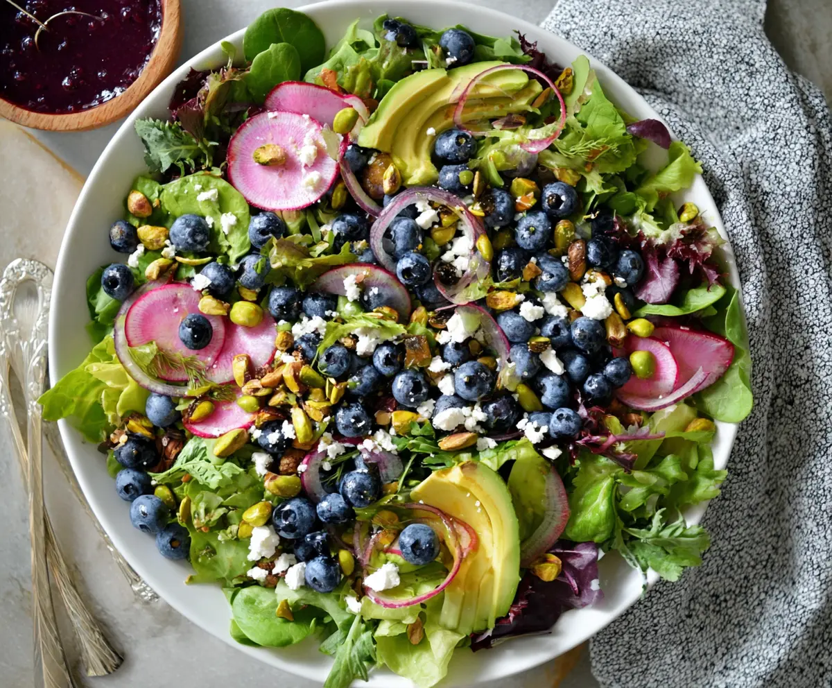 Colorful blueberry pistachio spring salad with fresh greens and vibrant toppings.
