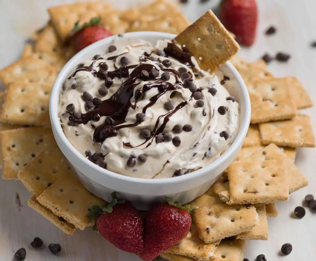 Creamy chocolate chip dessert dip served with cookies for a sweet snack.