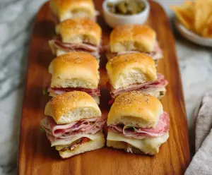 Delicious Muffuletta Sliders with layers of Italian meats, cheeses, and olive salad on mini buns.