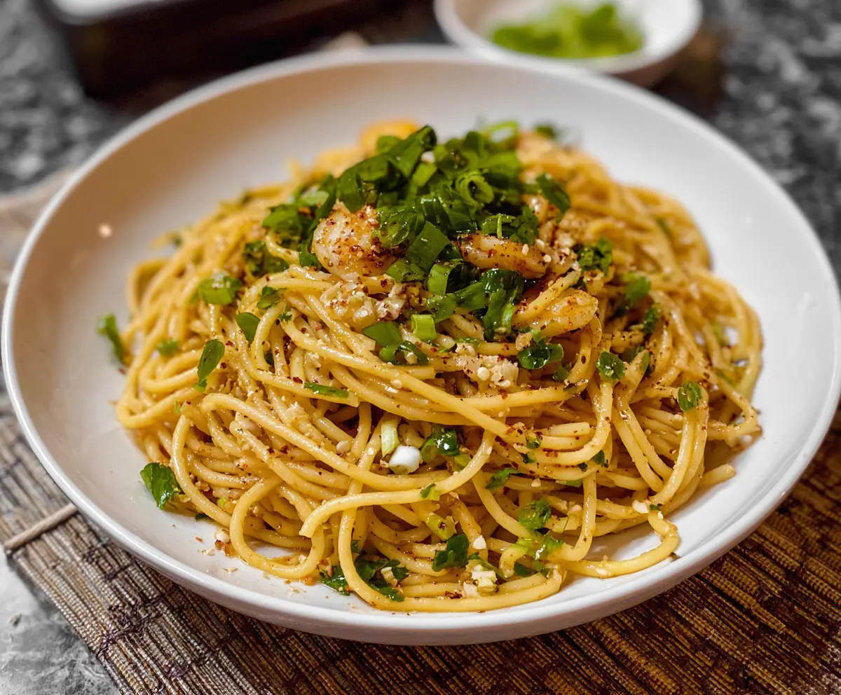 Plate of flavorful Vietnamese garlic noodles garnished with fresh herbs and crispy vegetables.