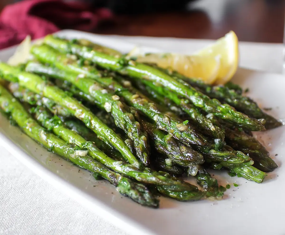 Delicious garlic butter asparagus spears garnished with fresh herbs on a white plate