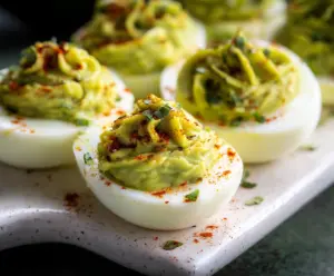 Delicious avocado deviled eggs topped with paprika and fresh herbs